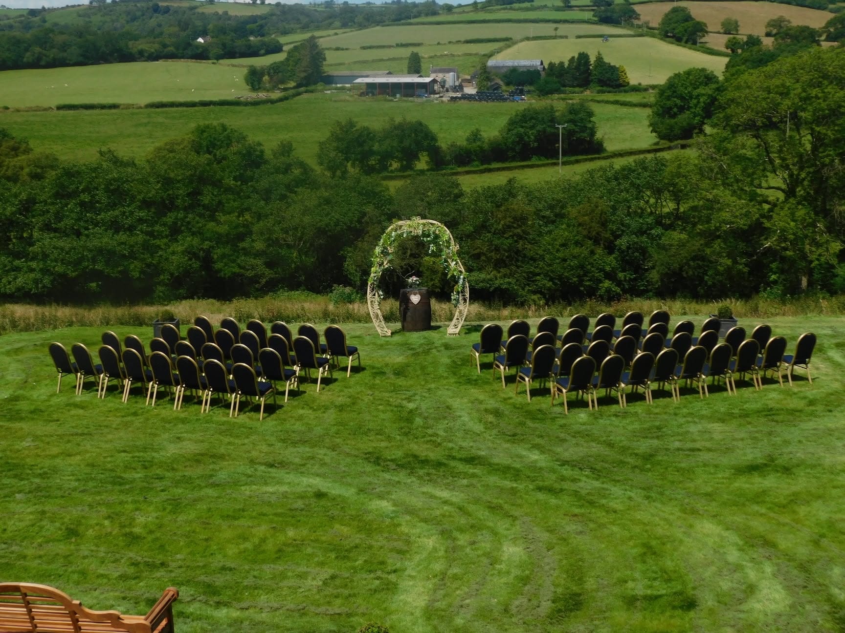 Outdoor wedding ceremony with floral arch and rows of chairs overlooking the Welsh countryside at Oak Tree Farm