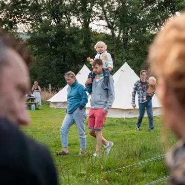 Family with young children enjoying the glamping field at Oak Tree Farm with white bell tents in the background