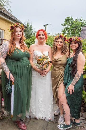 Bride with bridesmaids wearing flower crowns and green dresses at Oak Tree Farm