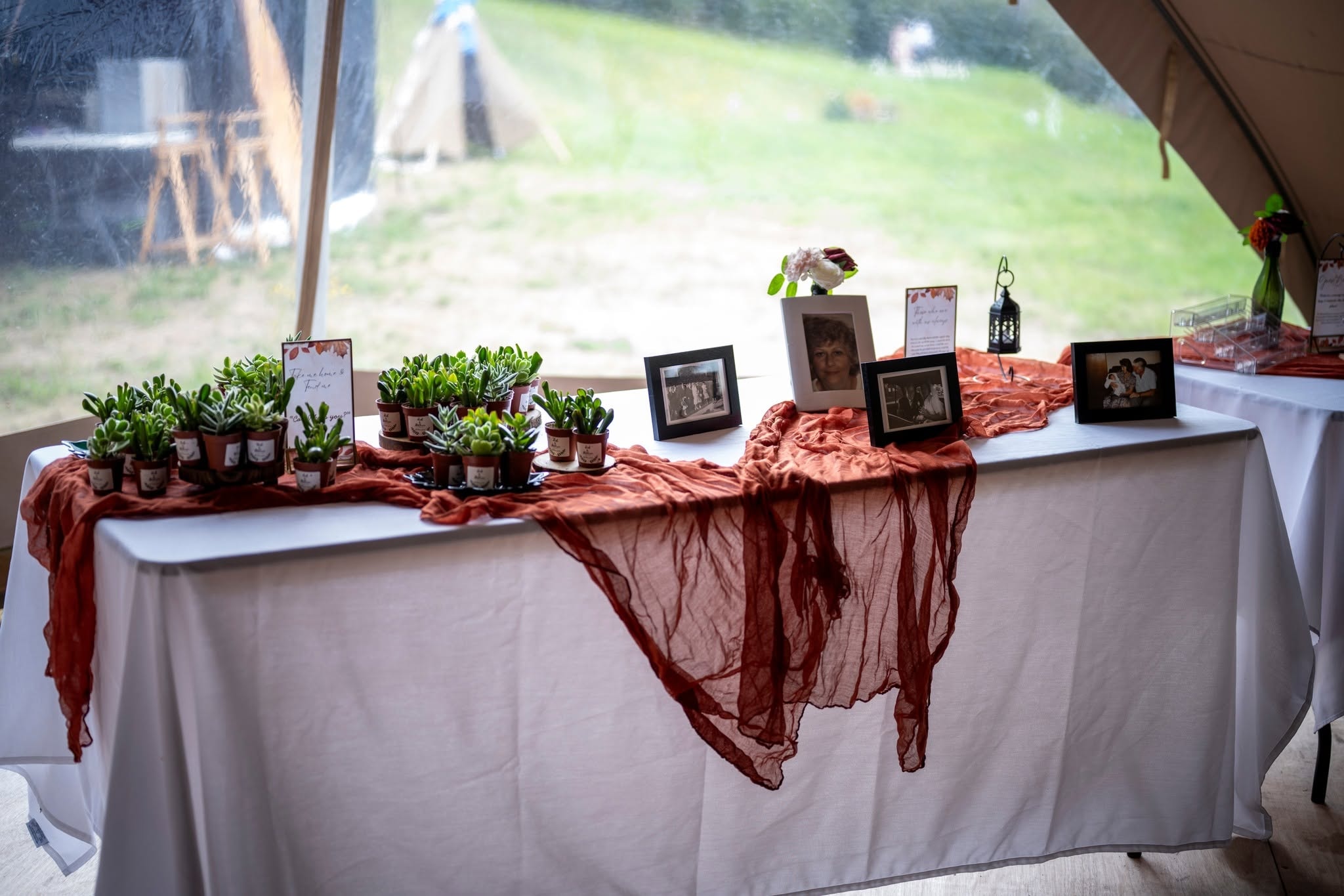 Beautifully decorated wedding reception table with succulent favours, framed photos and terracotta fabric runner