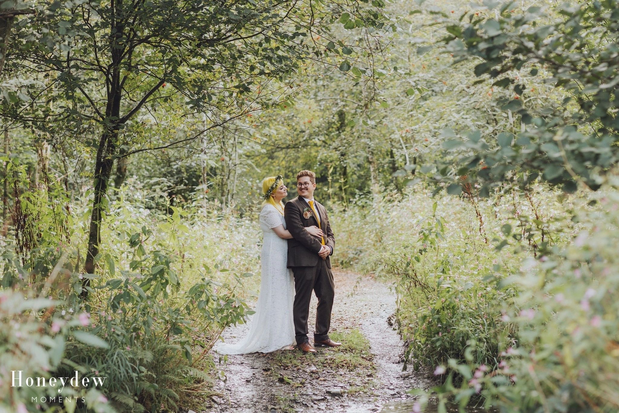 Bride and groom walking through a woodland path